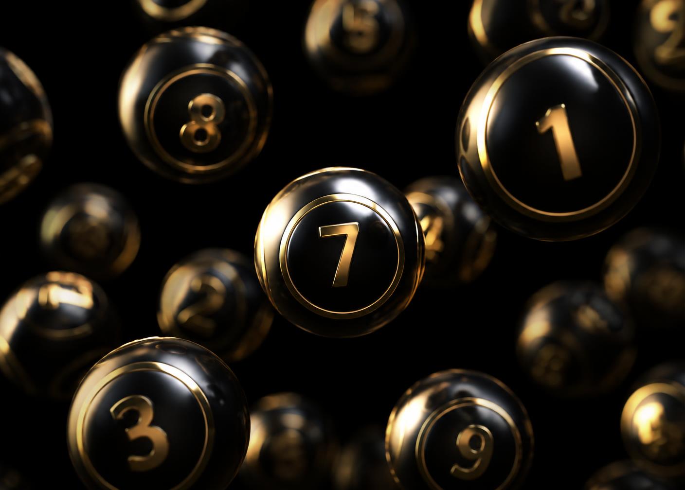 Glossy black and gold lottery balls suspended in darkness